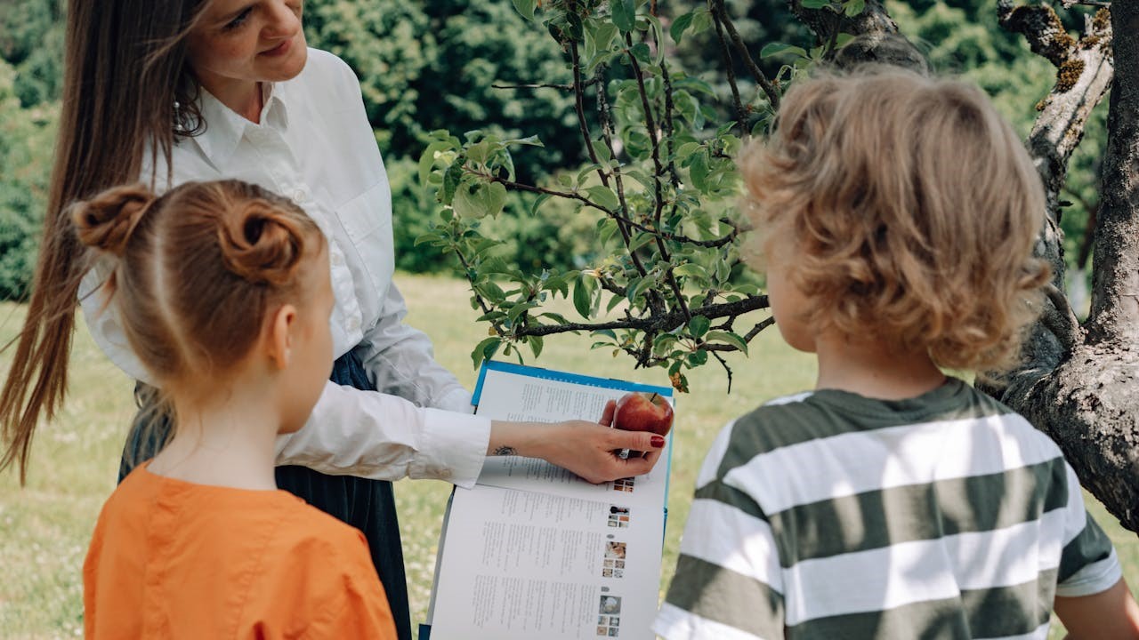 Vrouw leert kinderen iets over appel - Mikhail Nilov via Pexels